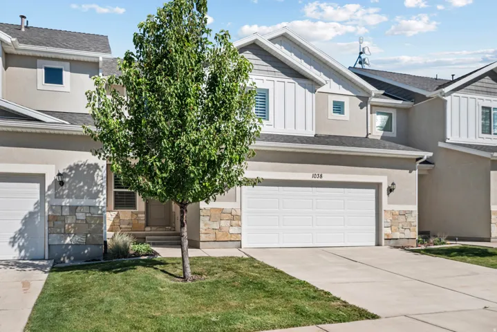 Stucco exterior with stone accents, attached garage, and a concrete driveway