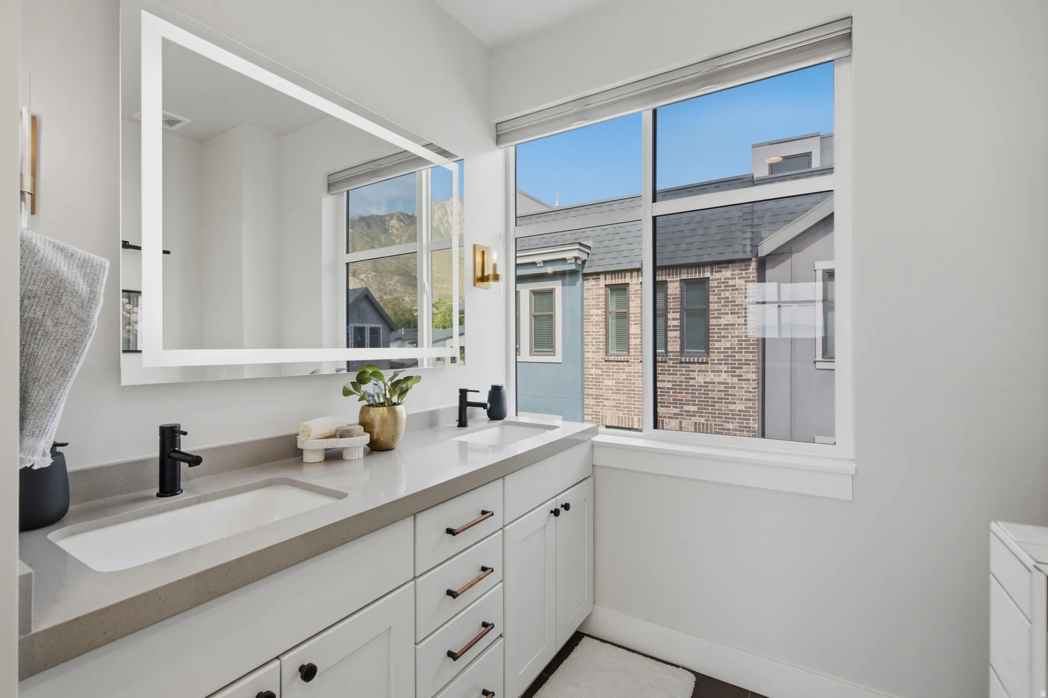 Dual vanity with integrated rectangular sinks, stone countertop, white shaker cabinetry, and matte black fixtures