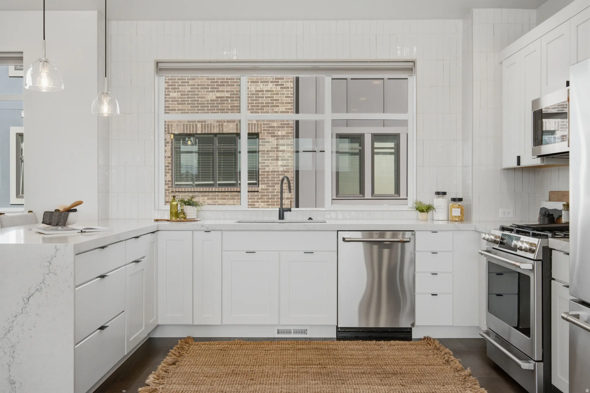 White kitchen cabinetry with integrated stainless steel appliances and wood-finish flooring