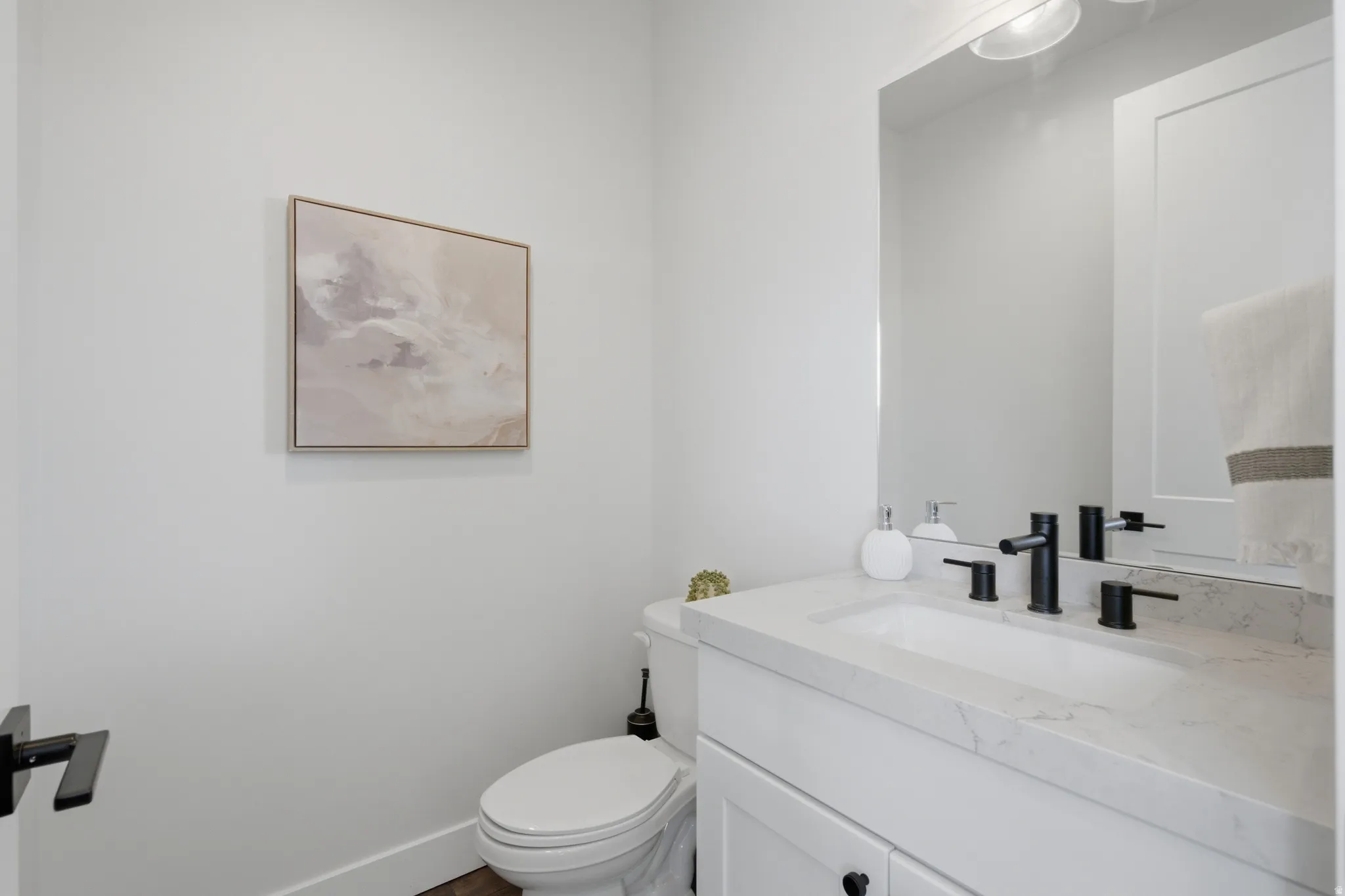 Bright powder room featuring a white vanity with marble-top countertop, rectangular vessel sink, and matte black faucet fixtures