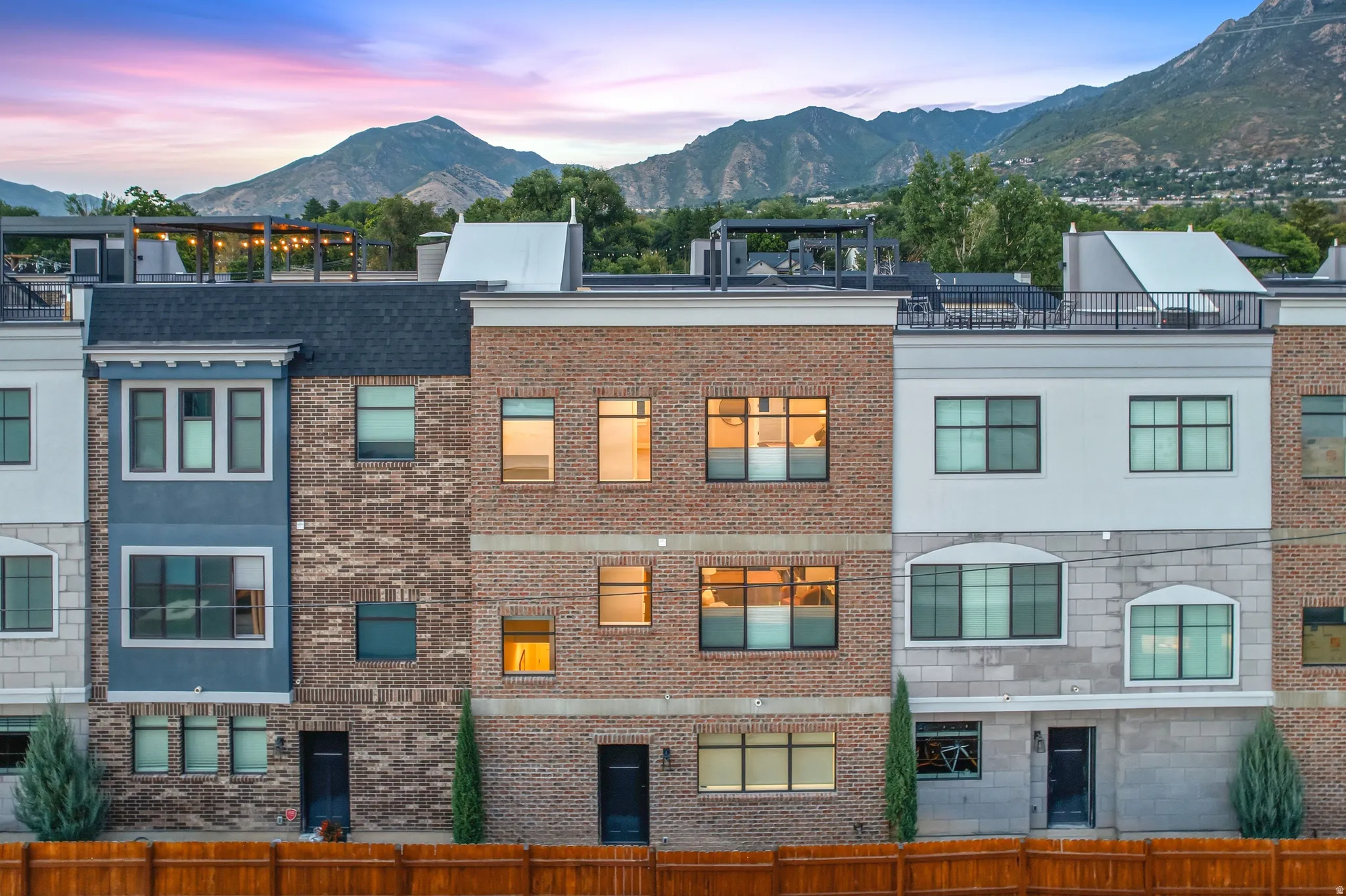 Townhomes featuring brick and stucco exteriors, varied window styles, and flat rooftops with railings