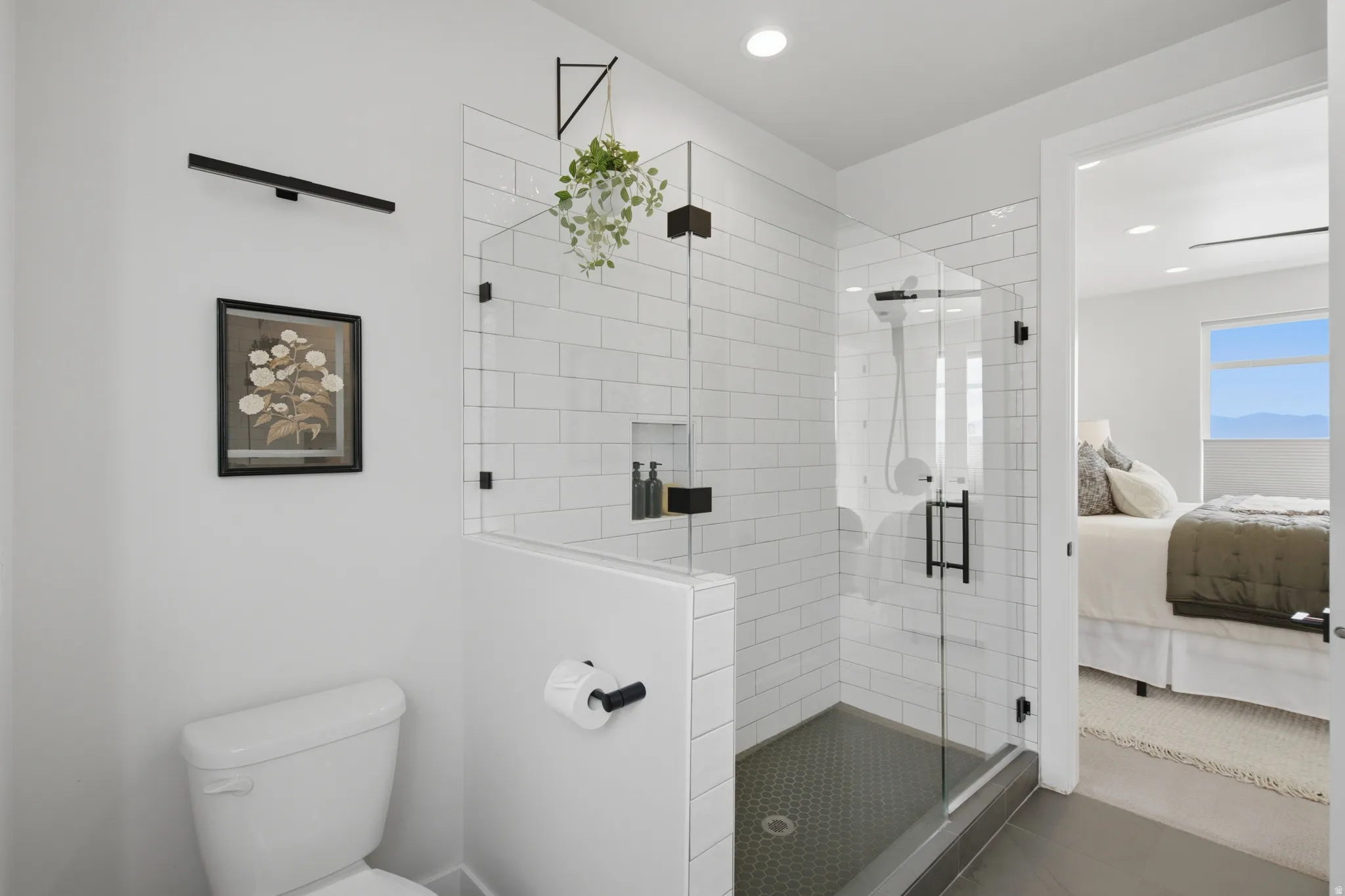 Full glass shower enclosure with white subway tile surround, dark hexagonal tile shower floor, and matte black hardware