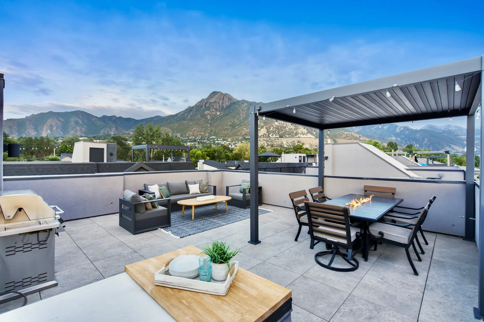 Expansive rooftop deck featuring a louvered pergola, durable tile flooring, and a built-in outdoor kitchen area