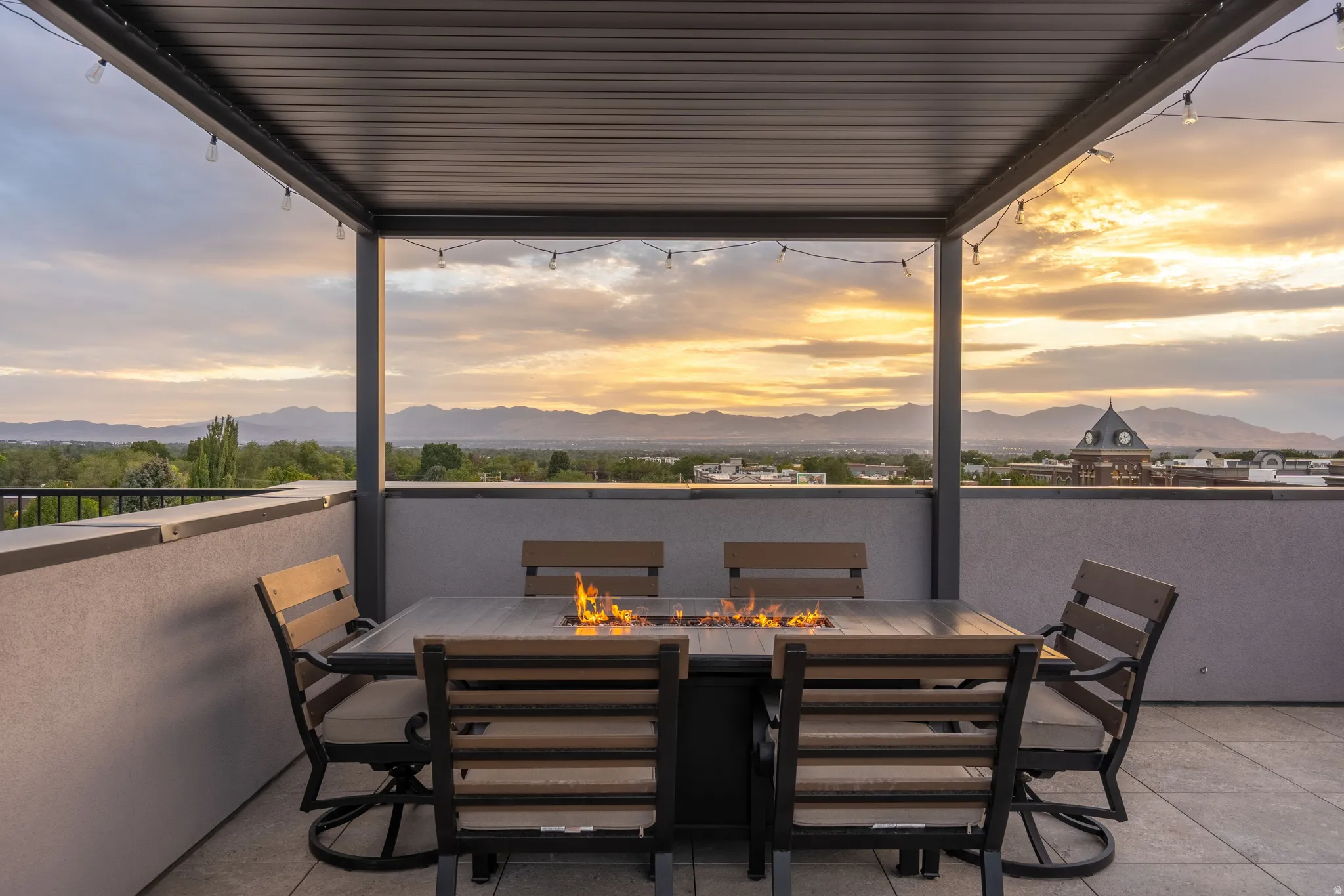 Rooftop patio featuring a metal pergola, string lighting, and a built-in fire pit