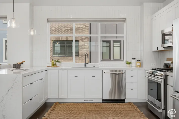 White kitchen cabinetry with integrated stainless steel appliances and wood-finish flooring