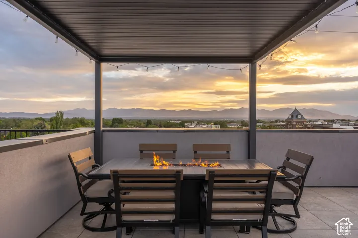 Rooftop patio featuring a metal pergola, string lighting, and a built-in fire pit