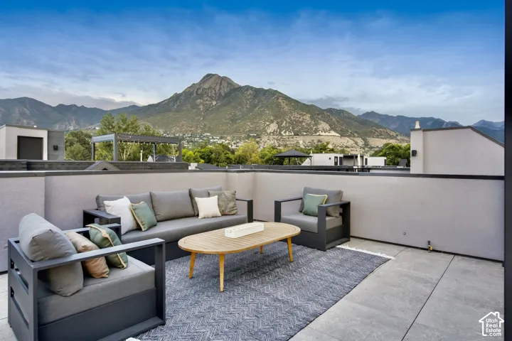 Expansive rooftop patio with mountain backdrop, concrete paver flooring, and perimeter wall