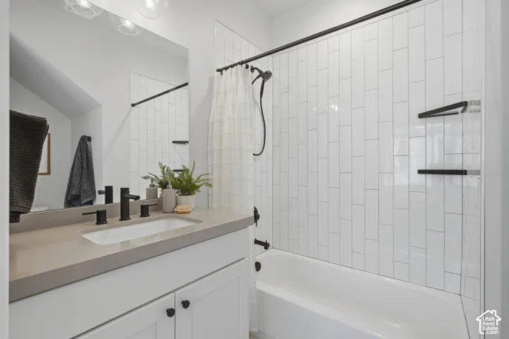 White subway tile shower surround with integrated shelves, matte black fixtures, white vanity with stone countertop, and an undermount sink