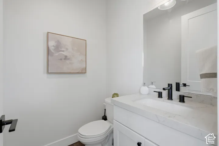 Bright powder room featuring a white vanity with marble-top countertop, rectangular vessel sink, and matte black faucet fixtures