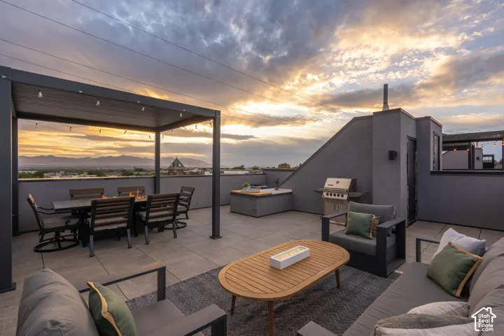 Rooftop deck featuring a metal pergola, paver flooring, built-in outdoor kitchen, and a stainless steel grill