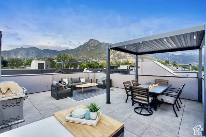 Expansive rooftop deck featuring a louvered pergola, durable tile flooring, and a built-in outdoor kitchen area