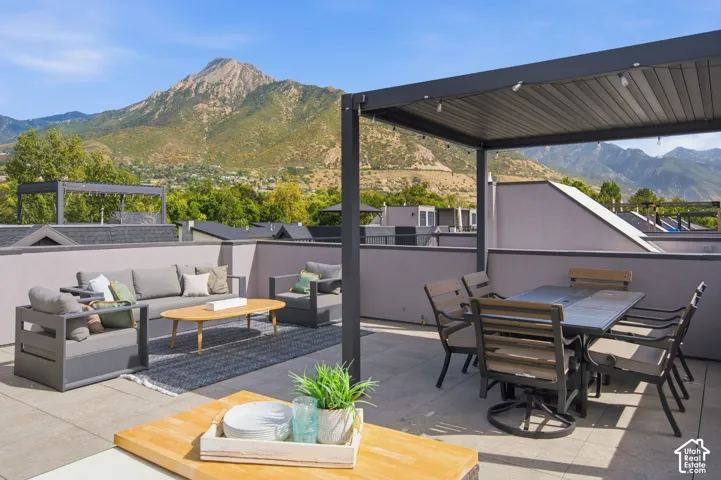 Rooftop patio featuring a slatted pergola, durable outdoor flooring, and a low privacy wall