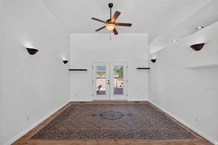 Vaulted ceiling, wood-finish flooring, ceiling fan, recessed lighting, and wall sconces