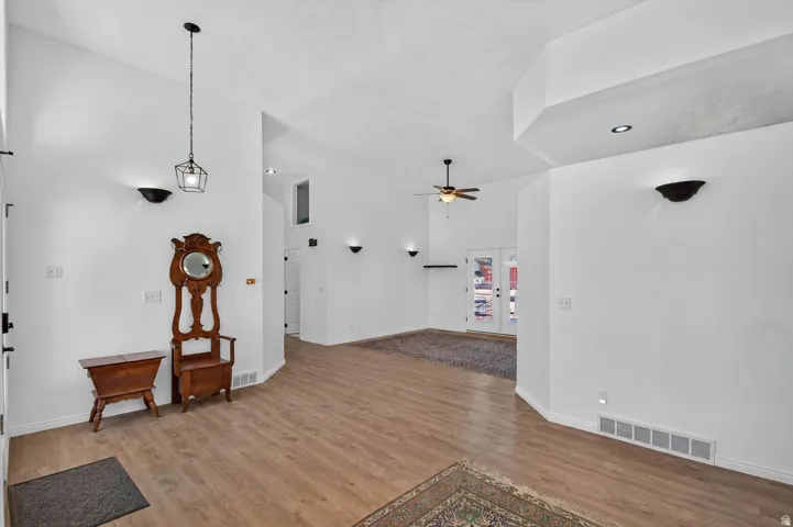 Wood-finish flooring, vaulted ceilings, recessed lighting, ceiling fan, and French doors with transom windows