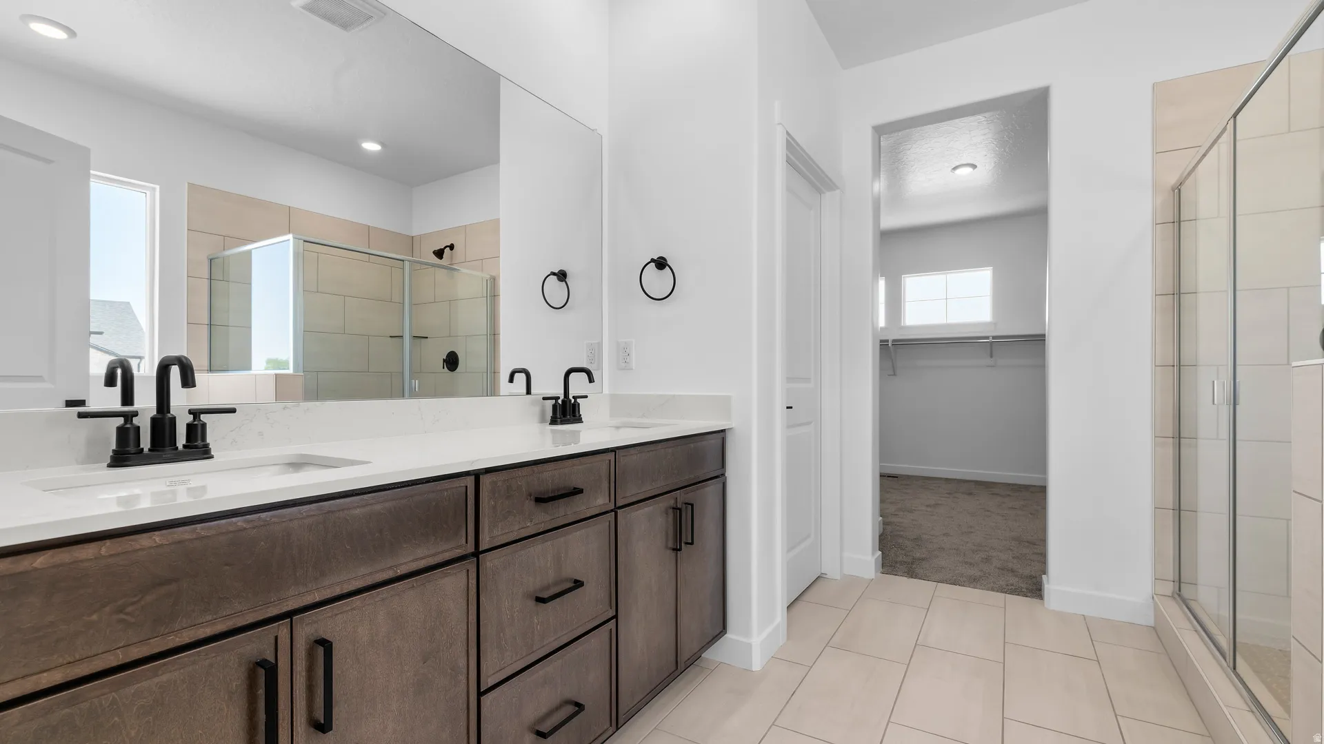 Dual vanity with stone-finish countertop, dark wood-finish cabinetry, and matte black fixtures
