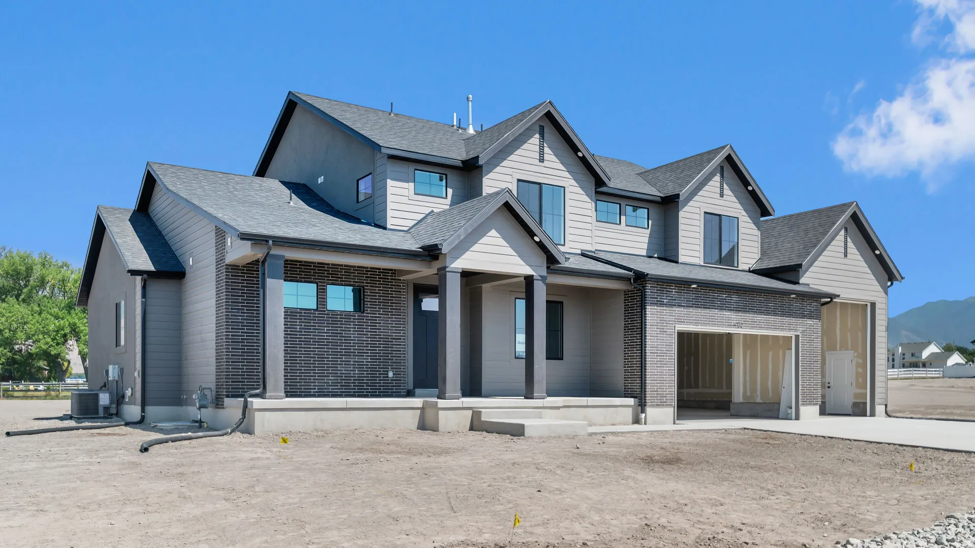 Contemporary exterior with gray siding and brick accents, multiple gables, and an attached garage