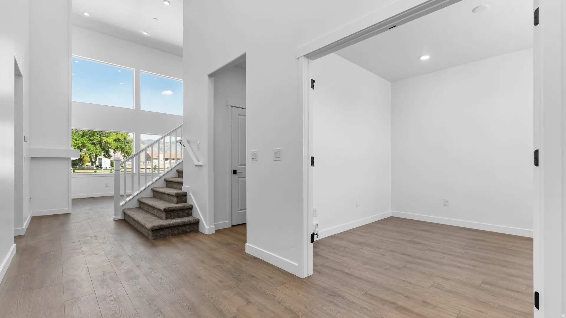 Two-story foyer with high ceilings, recessed lighting, expansive windows, and wood-finish flooring