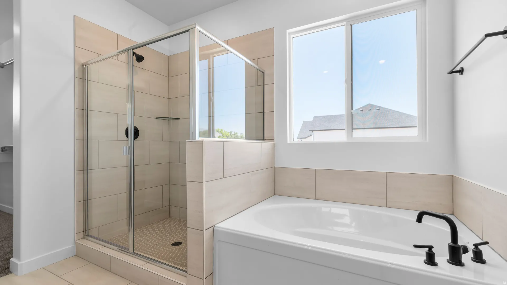 Built-in bathtub with matte black fixtures, tiled shower with glass enclosure, and a frosted window
