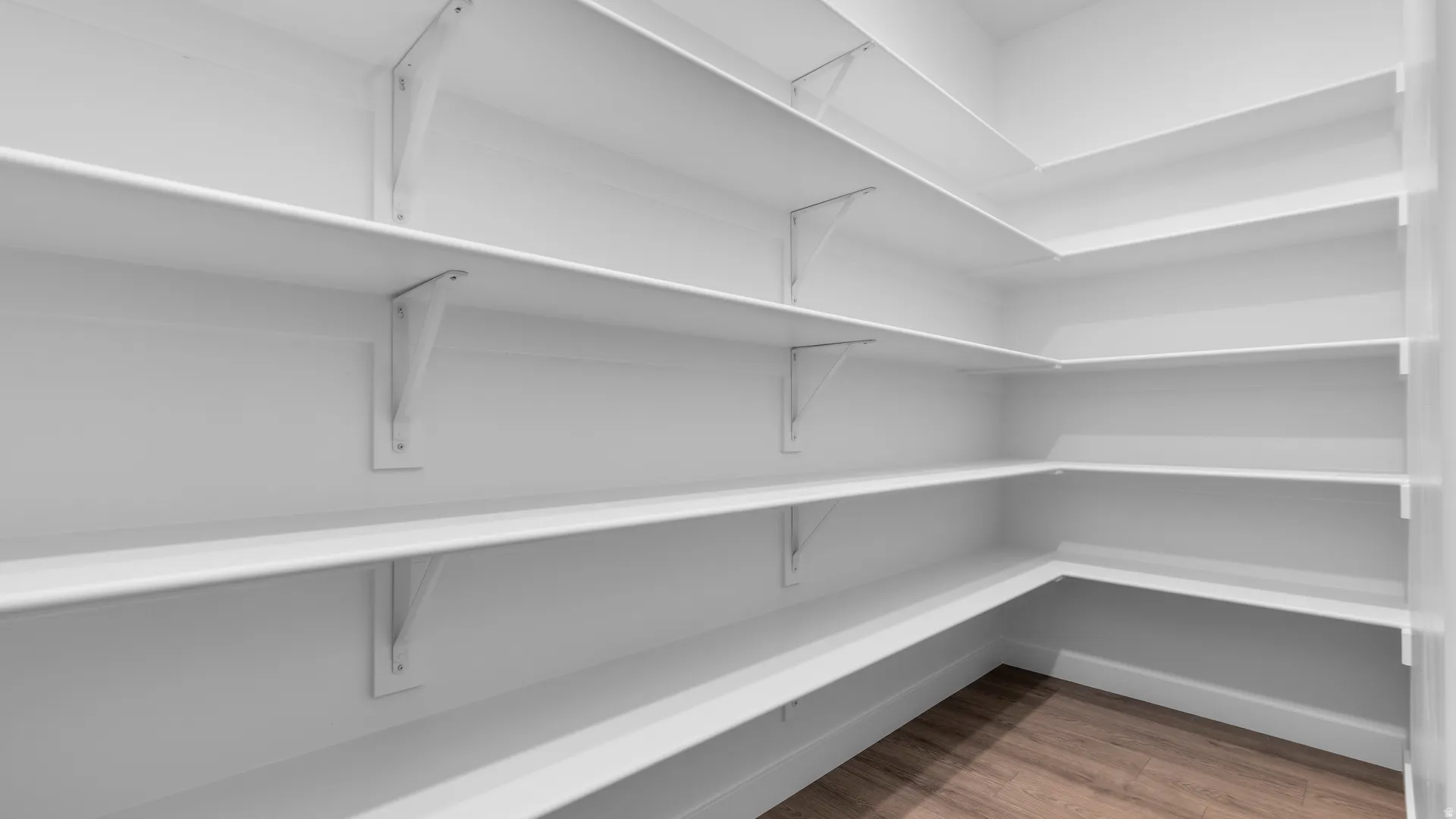 Integrated shelving, wood-finish flooring, white walls, corner shelving