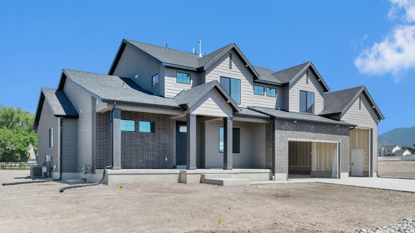 Contemporary exterior with gray siding and brick accents, multiple gables, and an attached garage