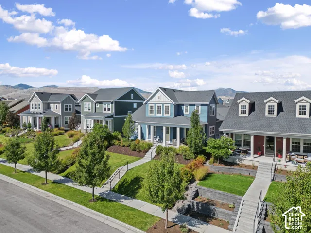 Residential street featuring diverse architectural styles, landscaped front yards with mature trees, and concrete sidewalks