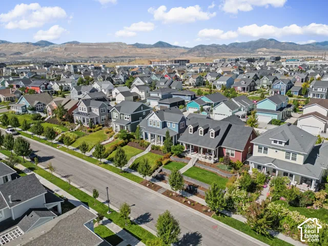 Residential neighborhood with varied architectural styles, manicured lawns, and mature trees, set against a mountainous backdrop