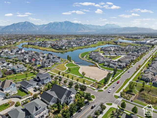 Lakeside community featuring residential properties, manicured green spaces, paved pathways, and mountain scenery