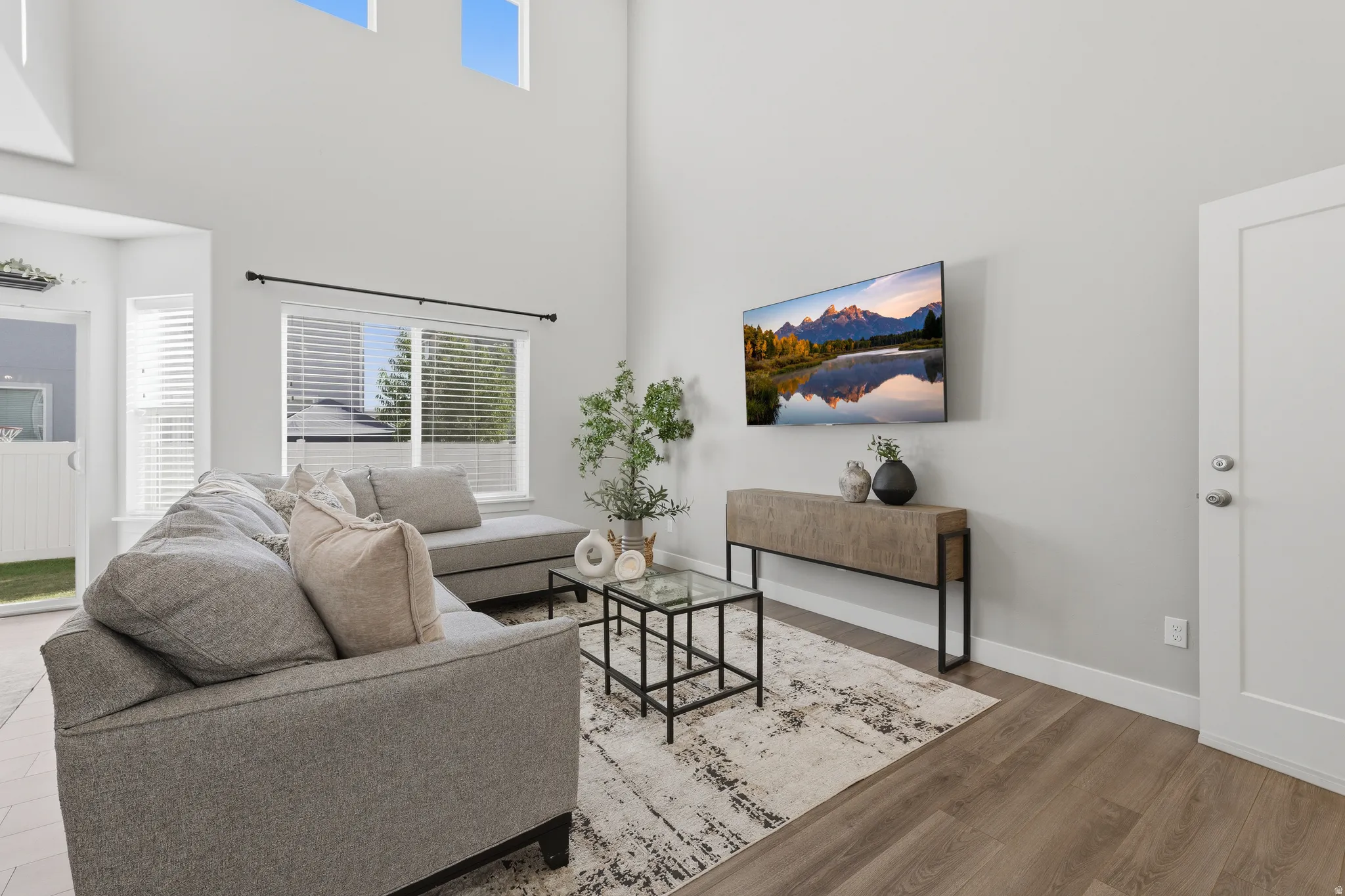 Vaulted ceilings, expansive windows, wood-finish flooring, and a contemporary light color palette