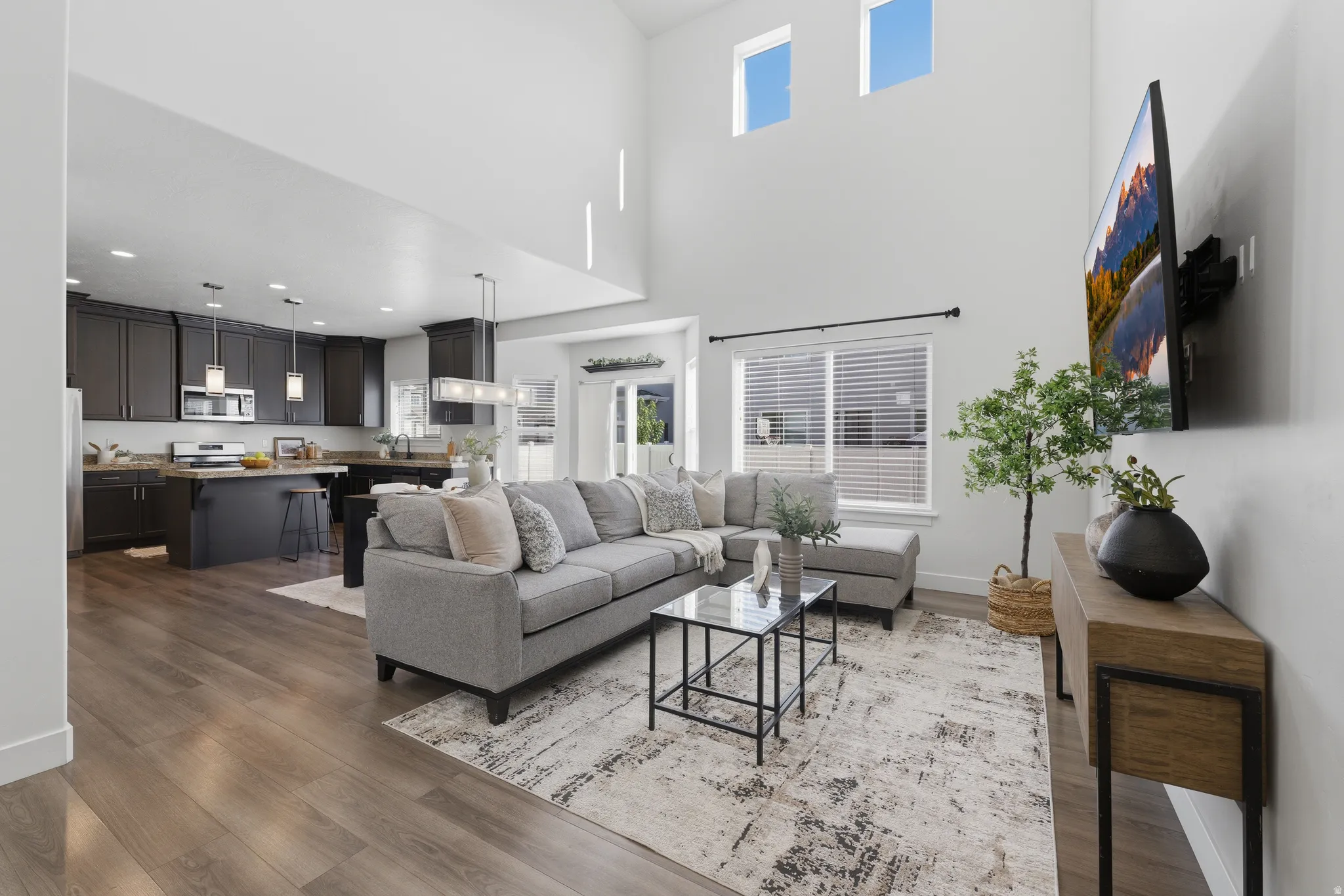 Soaring vaulted ceilings, wood-finish flooring, dark wood cabinetry, an island with seating, and stainless steel appliances