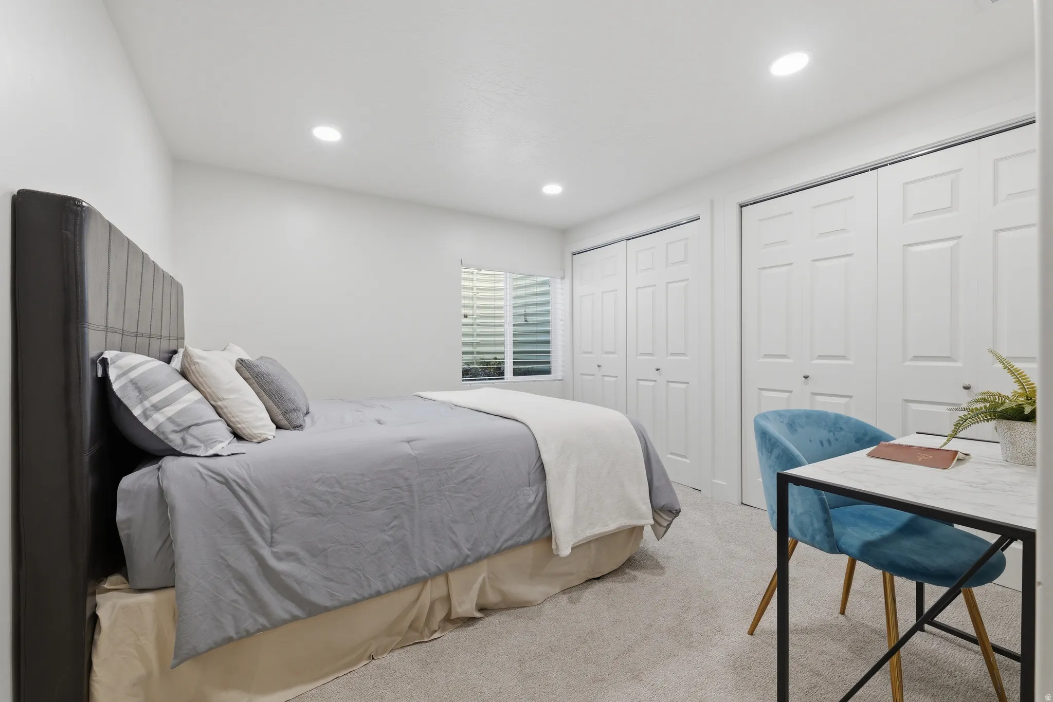 Recessed ceiling lighting, multiple bifold closet doors, light-toned carpeting, and a window with horizontal blinds