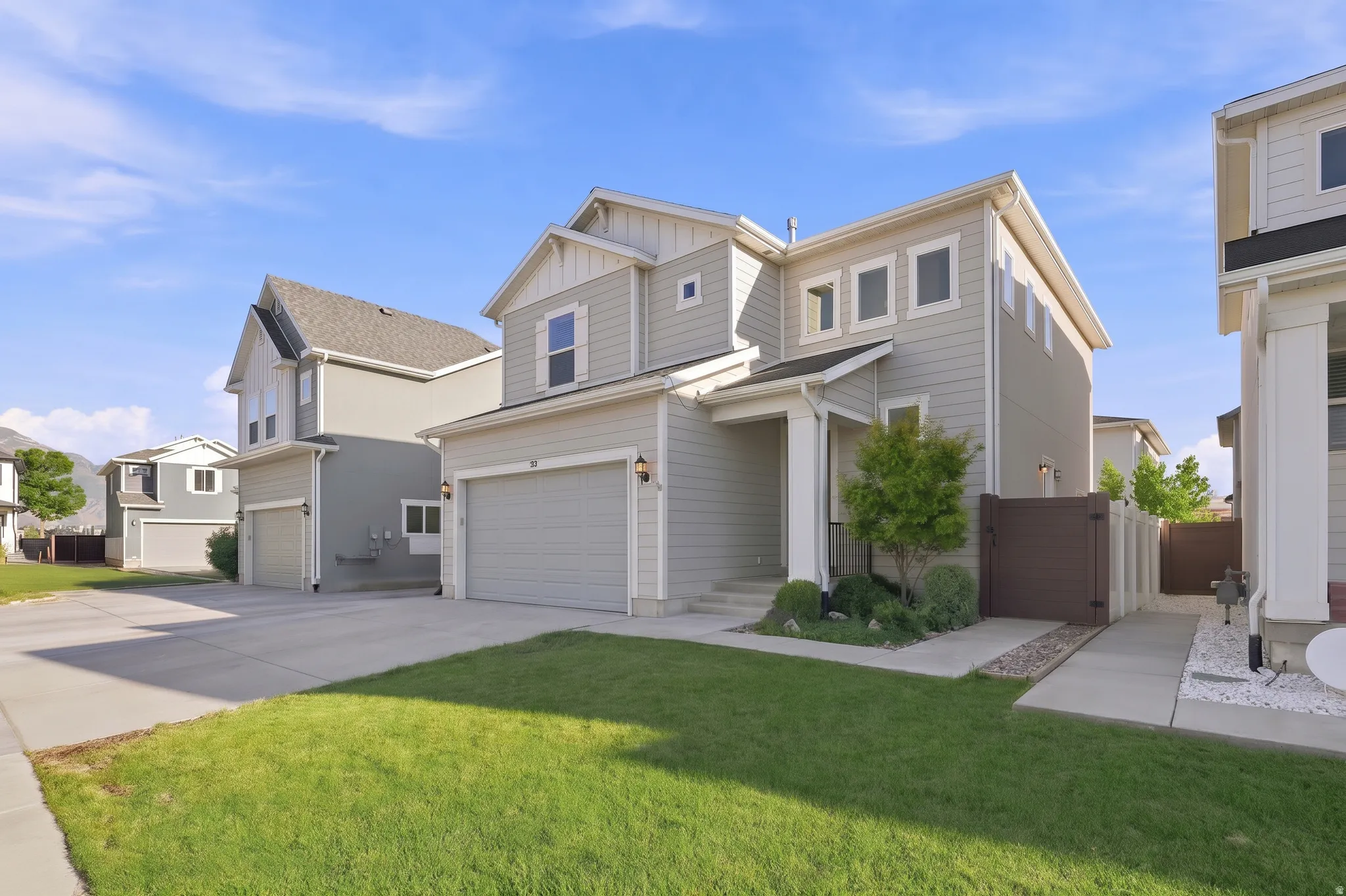 Light grey siding exterior with white trim and gables, a two-car garage, and a covered entry
