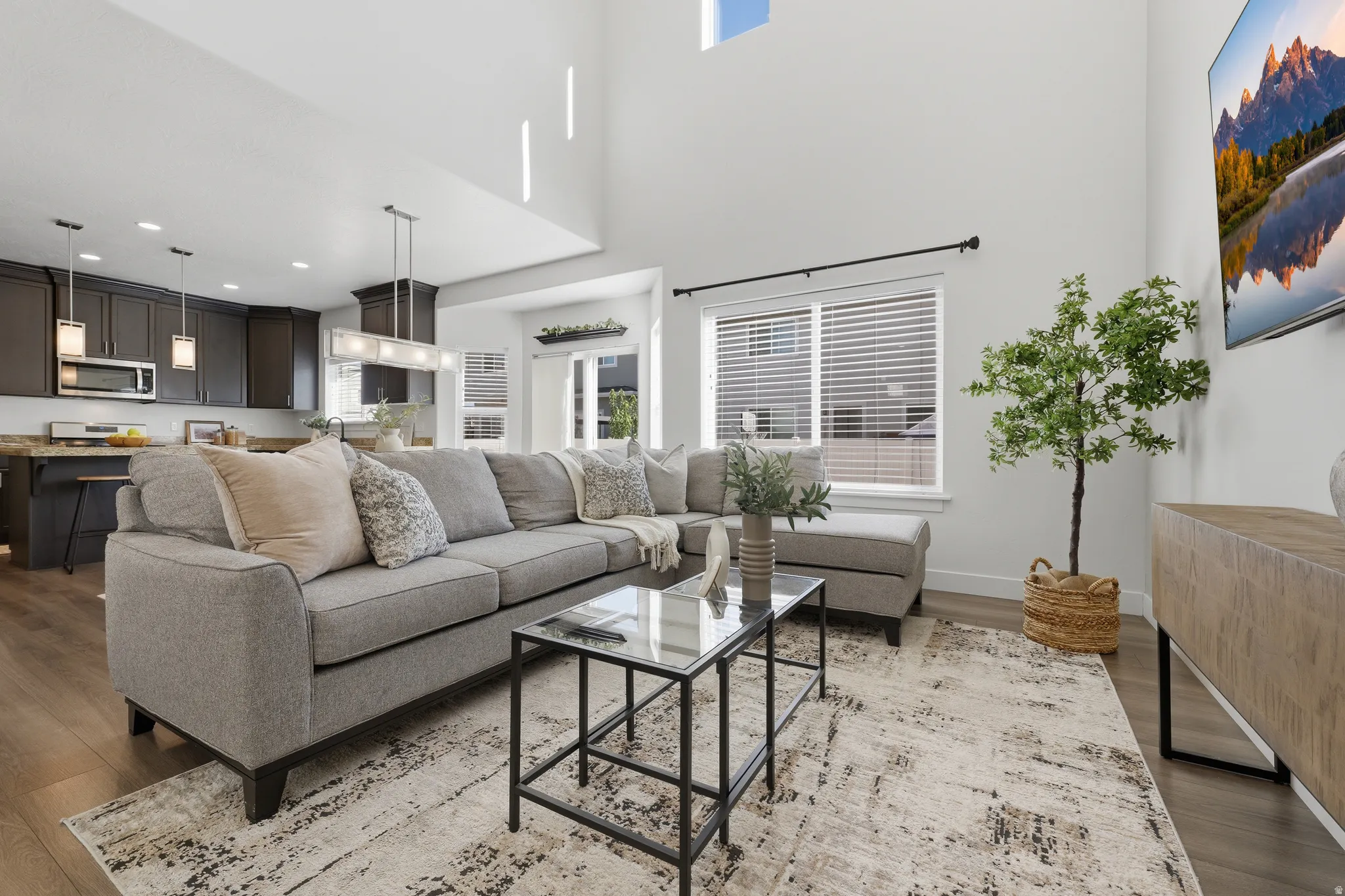 Vaulted ceilings with high windows, wood-finish flooring, dark cabinetry, and recessed lighting