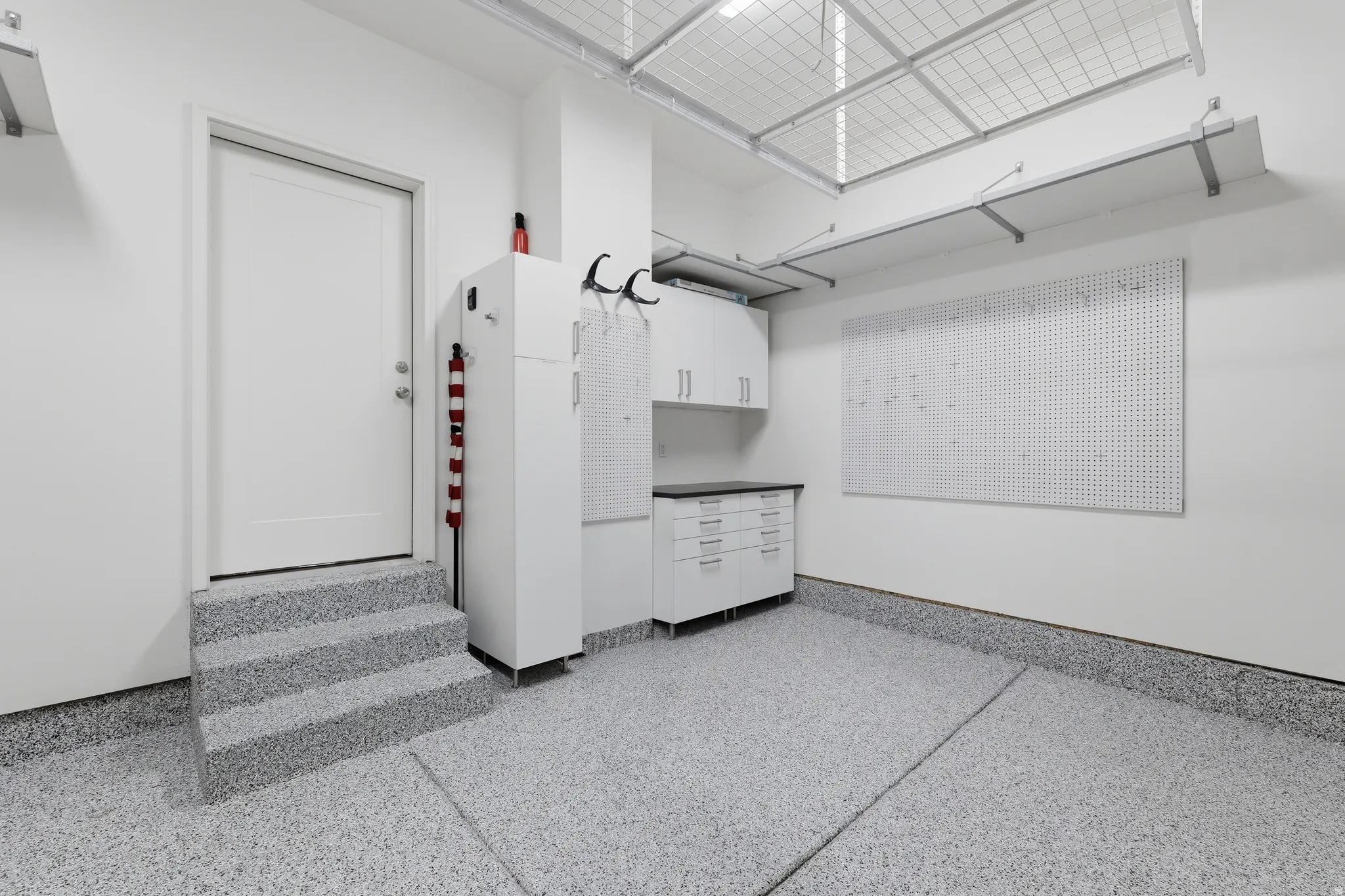 Epoxy-coated flooring, built-in cabinetry, pegboard wall, and overhead storage racks