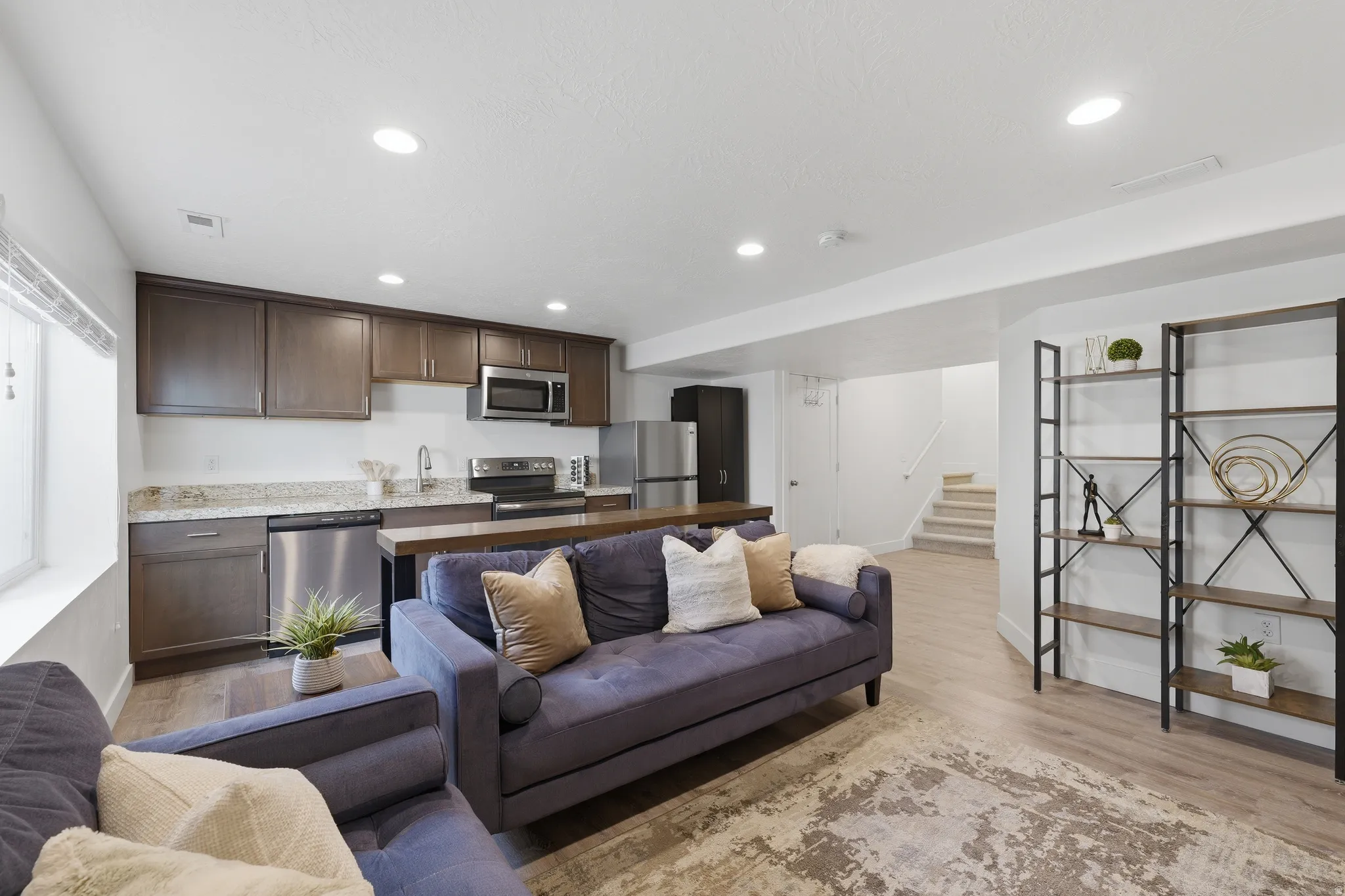 Kitchenette featuring dark wood-finish cabinetry, stainless steel appliances, and a granite-style countertop