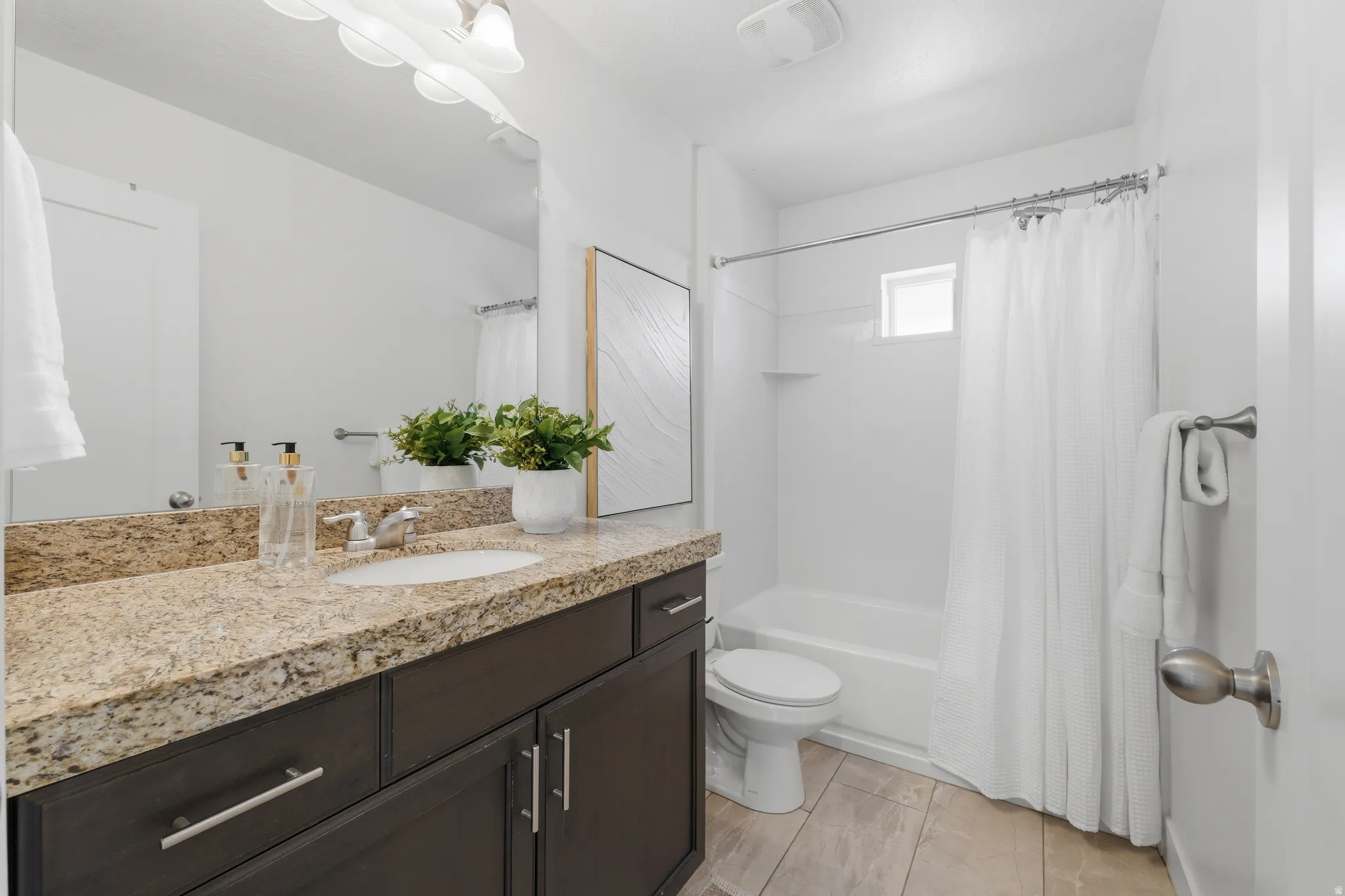 Vanity with a light-colored stone countertop, dark wood-finish cabinetry, and an undermount sink