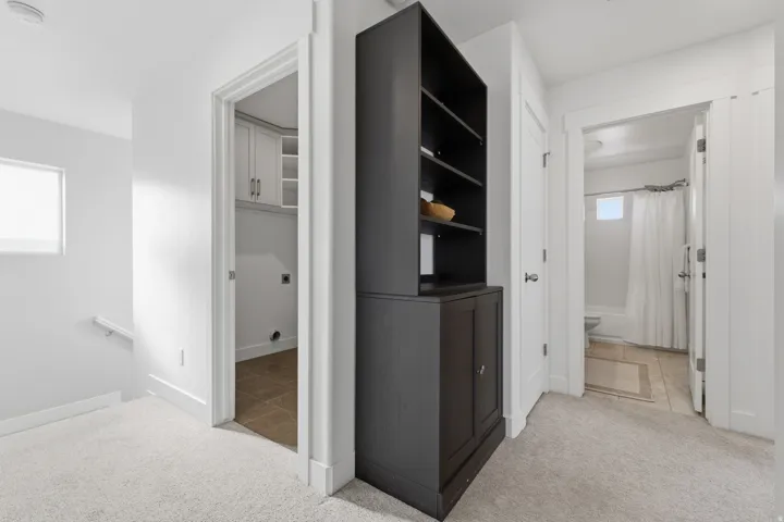 Neutral tone carpeting, white walls, built-in shelving with cabinet storage, and white interior doors