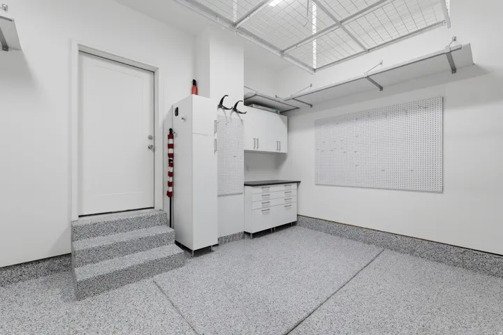 Epoxy-coated flooring, built-in cabinetry, pegboard wall, and overhead storage racks