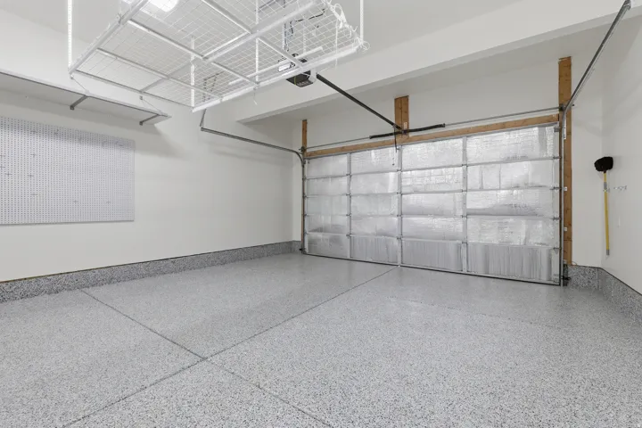 Epoxy-coated flooring, insulated garage door, integrated wall organization system, overhead storage racks, and white wall finishes