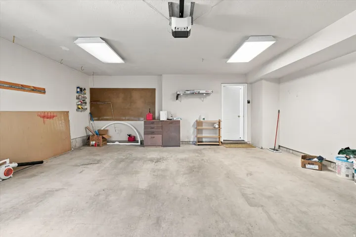 Garage featuring a concrete floor, white painted walls, and overhead lighting