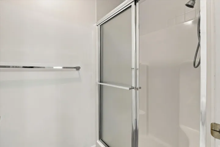 Shower with frosted glass enclosure, chrome fixtures, and a tiled shower wall