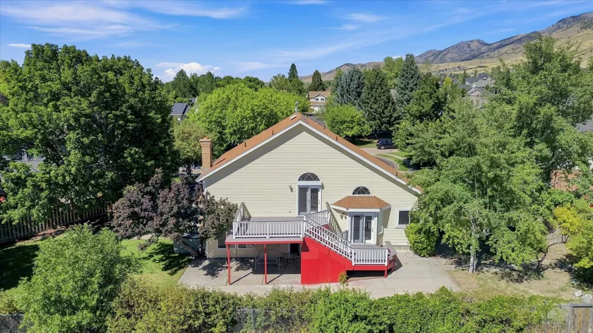 Expansive property featuring a two-story deck, bay window, and a backdrop of mountainous terrain