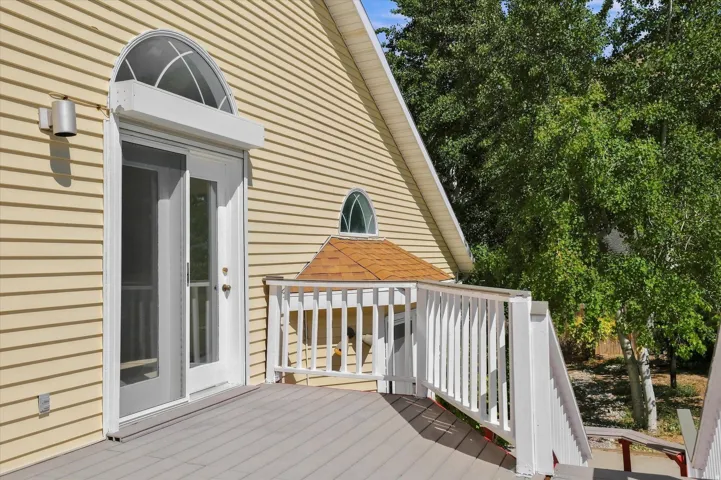 Deck with white railings, featuring a sliding glass door with an arched transom window