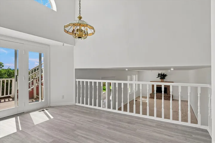 High ceilings with an arched window, wood-finish flooring, and a decorative chandelier