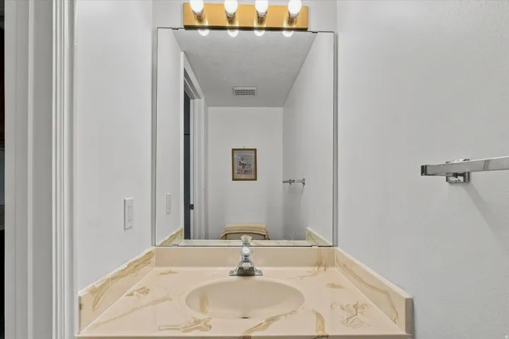 Single vanity with an integrated sink and light-toned countertop, framed mirror, and chrome faucet