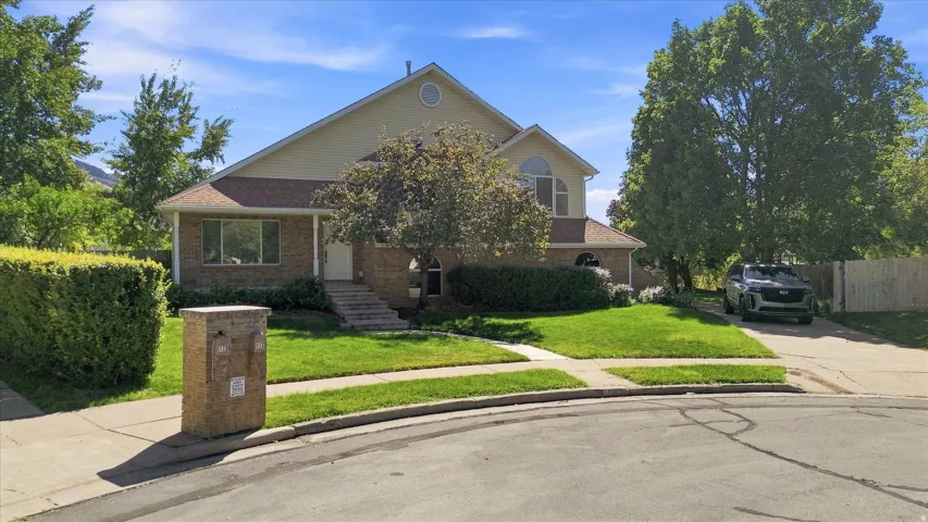 Two-story residence featuring a partial brick facade, arched window details, and a concrete driveway