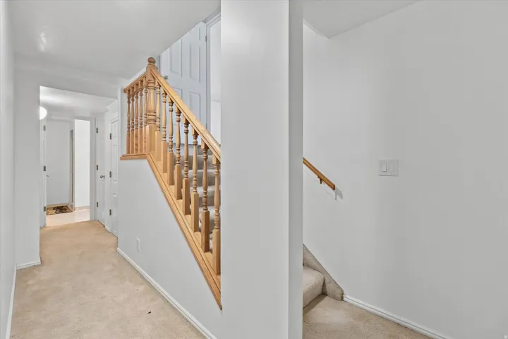 Carpeted staircase with wood-finish balusters and handrail