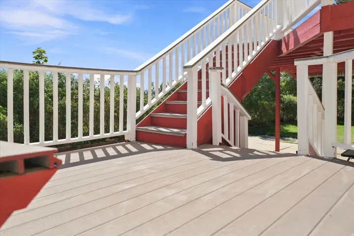 Wood-finish deck with white baluster railing and red-painted support structure