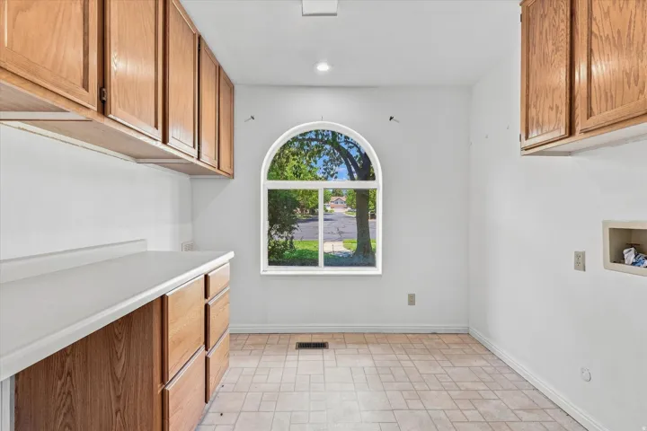 Arched window, recessed lighting, wood-finish cabinetry, light-toned countertop, and tiled flooring