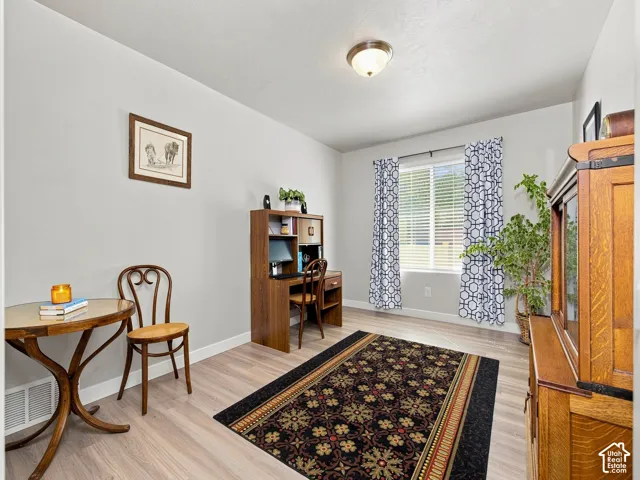 Light wood-finish flooring, recessed window with blinds, overhead flush mount light fixture, and light-toned wall paint