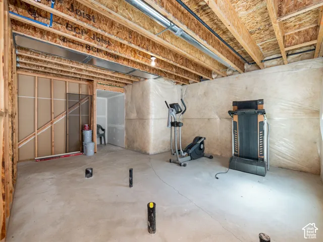 Unfinished lower level with exposed ceiling joists, visible ductwork, concrete flooring, and framed interior walls